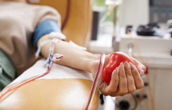 Close-up of patient with tubes in her arm squeezing the ball in her hand while donating the blood