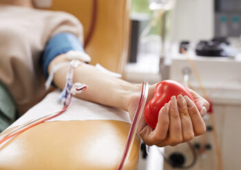 Close-up of patient with tubes in her arm squeezing the ball in her hand while donating the blood